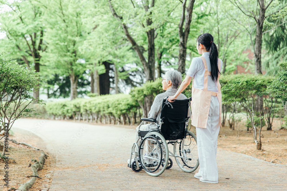 車いすの高齢の方に付き添うケアスタッフ
